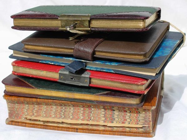 6 ältere Tagebücher liegen übereinander, zum Teil mit geöffneten Schlössern