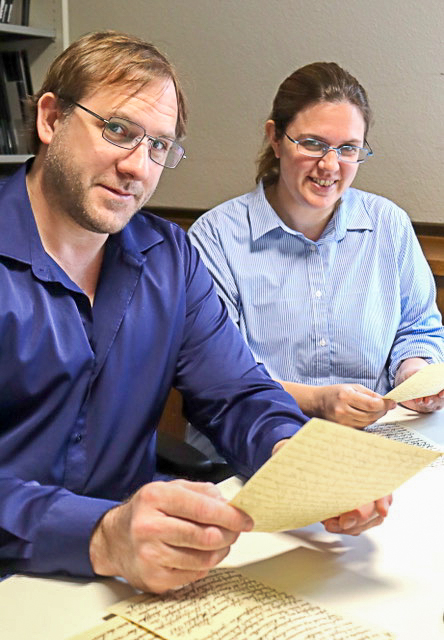 ein Mann und eine Frau schauen von ihren Papieren auf in die Kamera